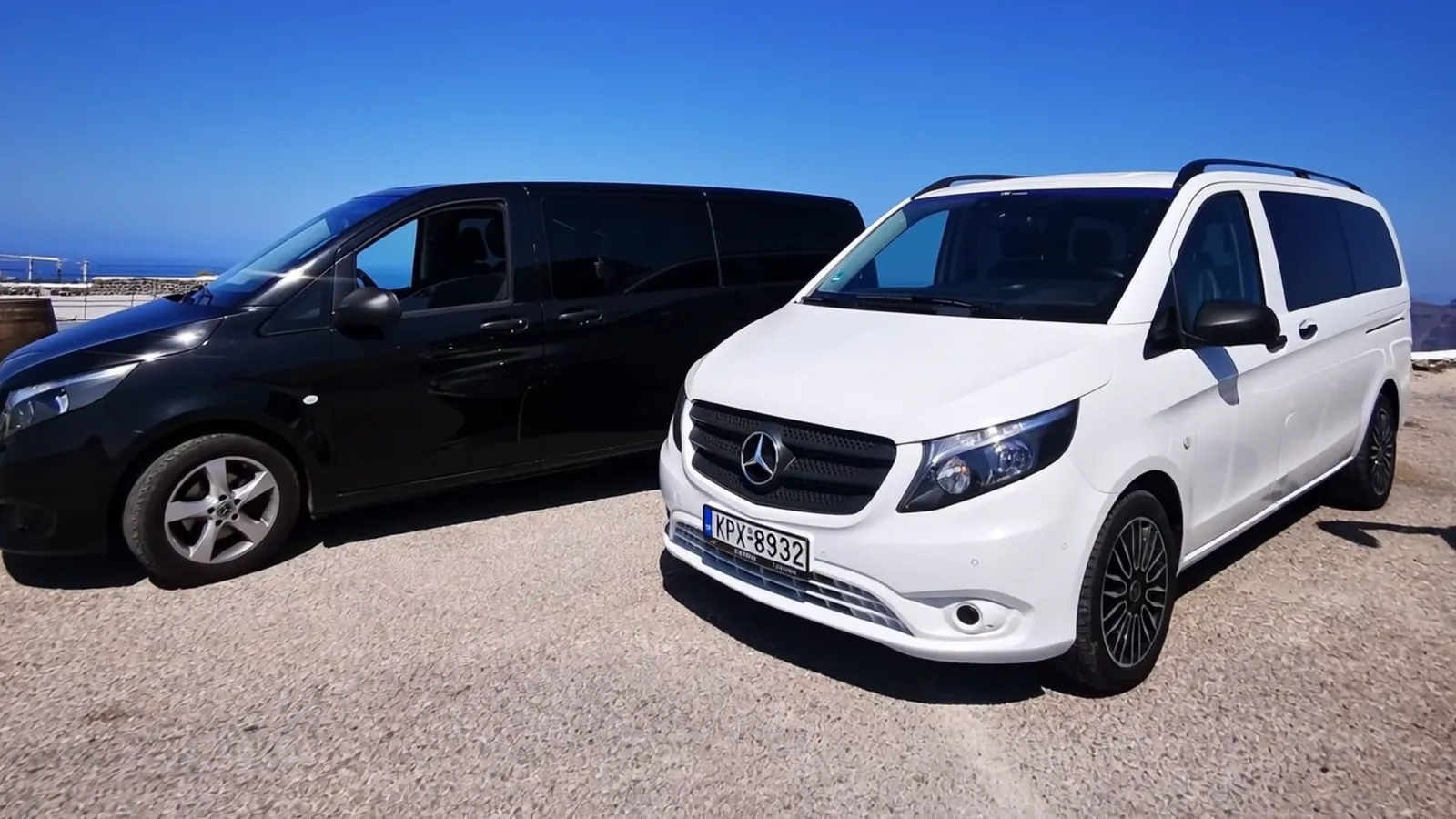 A white Mercedes-Benz Vito parked on a clifftop road above the Santorini caldera at golden hour