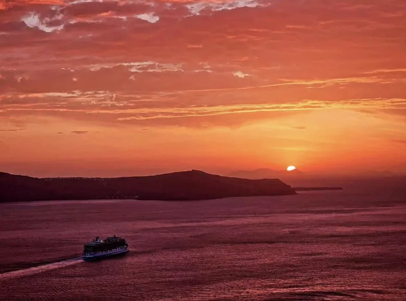 A ship crossing the caldera as the sun sets over Santorini
